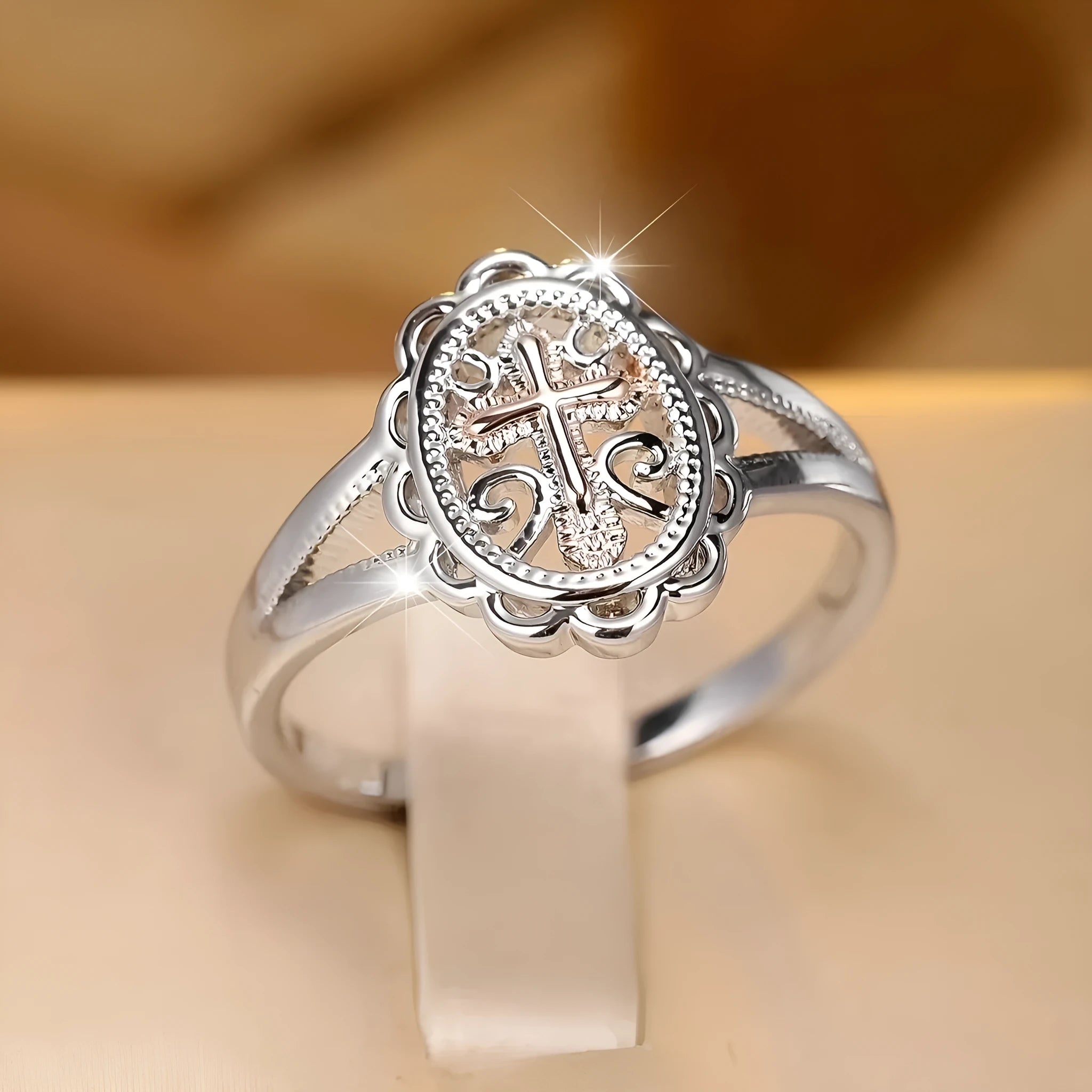 Silver women's ring with detailed cross and lace pattern, shown on a finger.