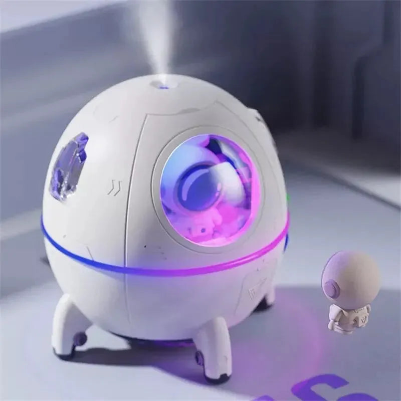 Light purple astronaut-shaped USB desktop humidifier with colourful LED light on a desk.