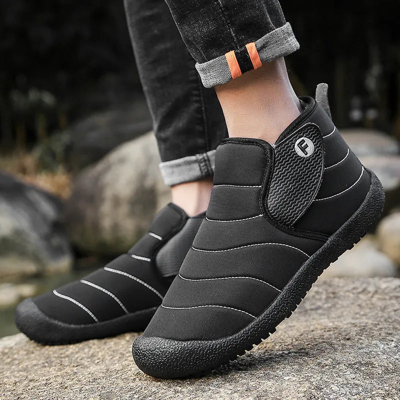 Men's thick black waterproof snow boots with a rubber sole on a hard surface.