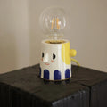 Handmade white ceramic table lamp with a spherical ball-shaped shade on a wooden surface.