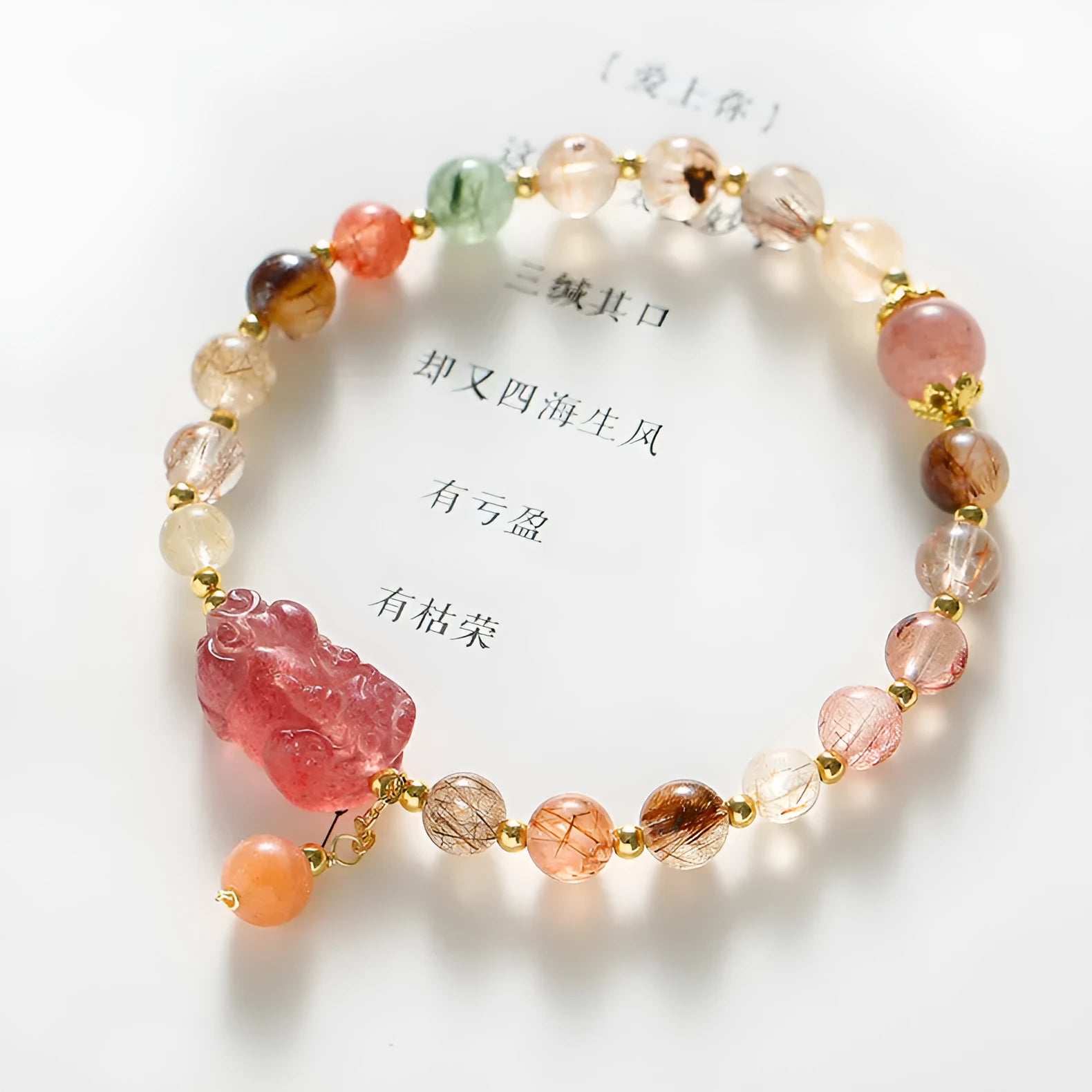 Close-up of a women's copper bracelet with a pink Strawberry Quartz crystal, a detailed Pixiu charm, and a white freshwater pearl.