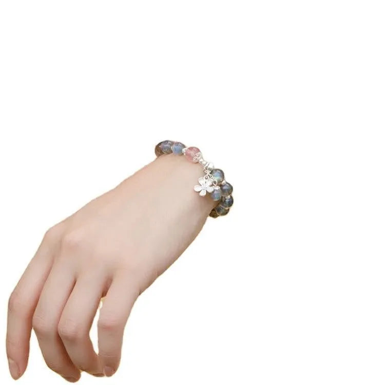 Close-up of a women's 925 sterling silver bracelet with a grey moonstone bead and a zodiac animal charm.