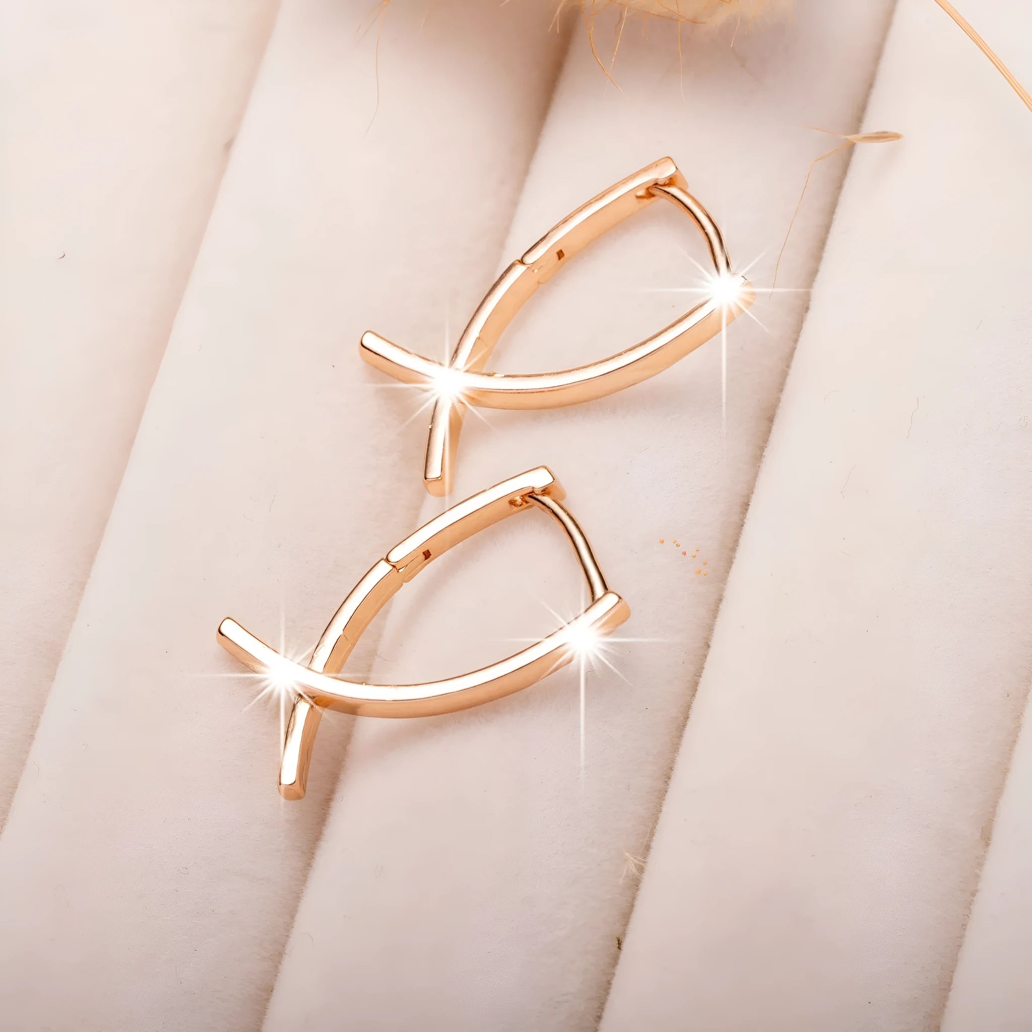 A pair of rose gold coloured cross shaped earrings on a copper metal base.
