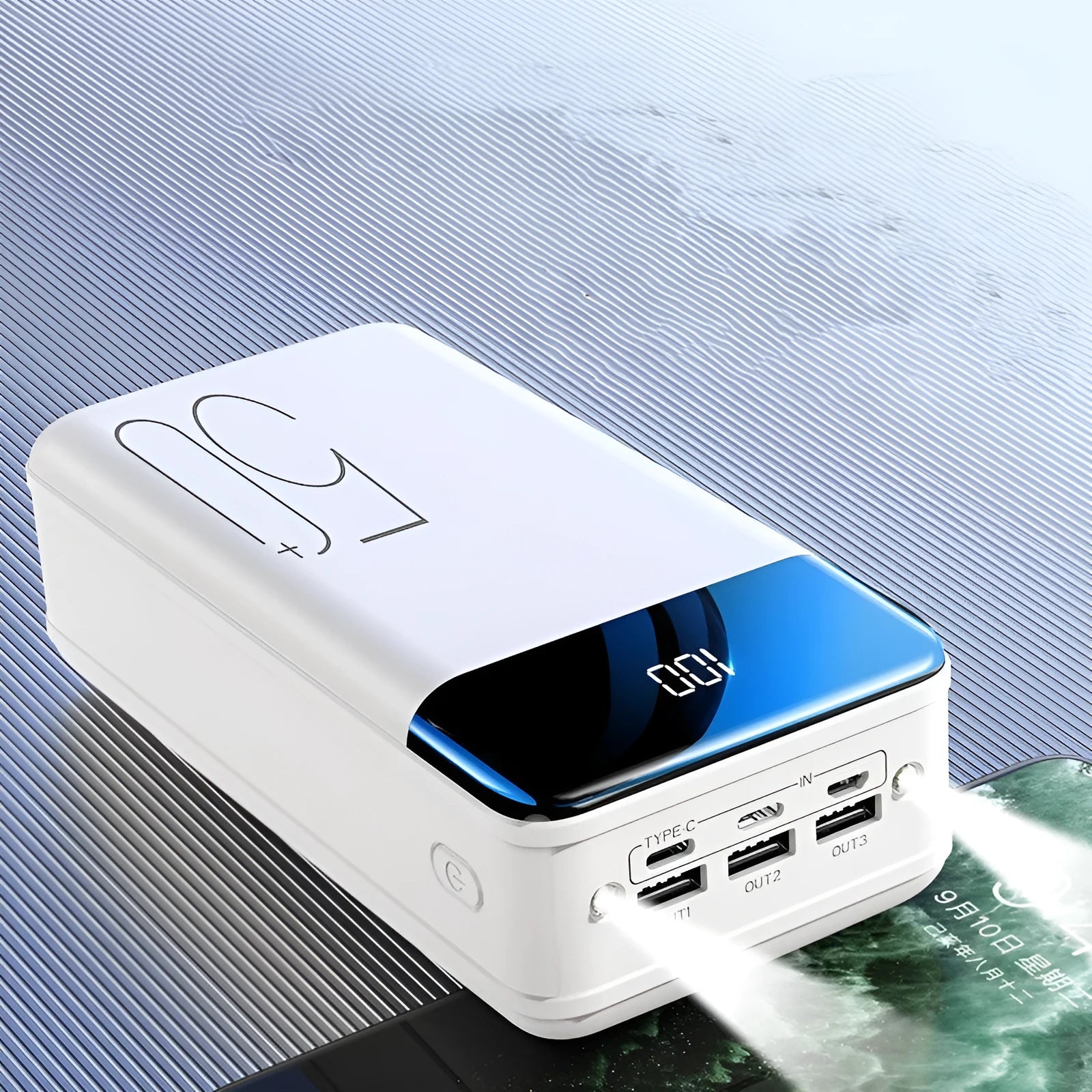 Black and white large 50000mAh portable power bank with multiple USB ports, showing scale next to a smartphone.