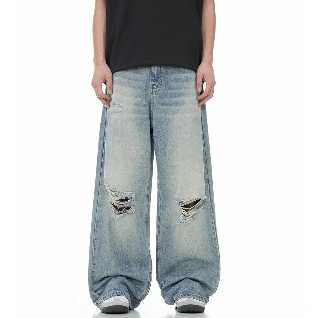 Man wearing blue ripped straight-leg jeans in a retro style with a zip fly.