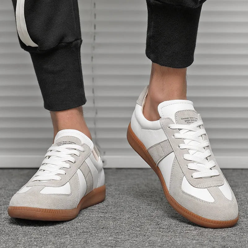 White low-top retro sneakers with round toe and lace-up front on a flat rubber sole.
