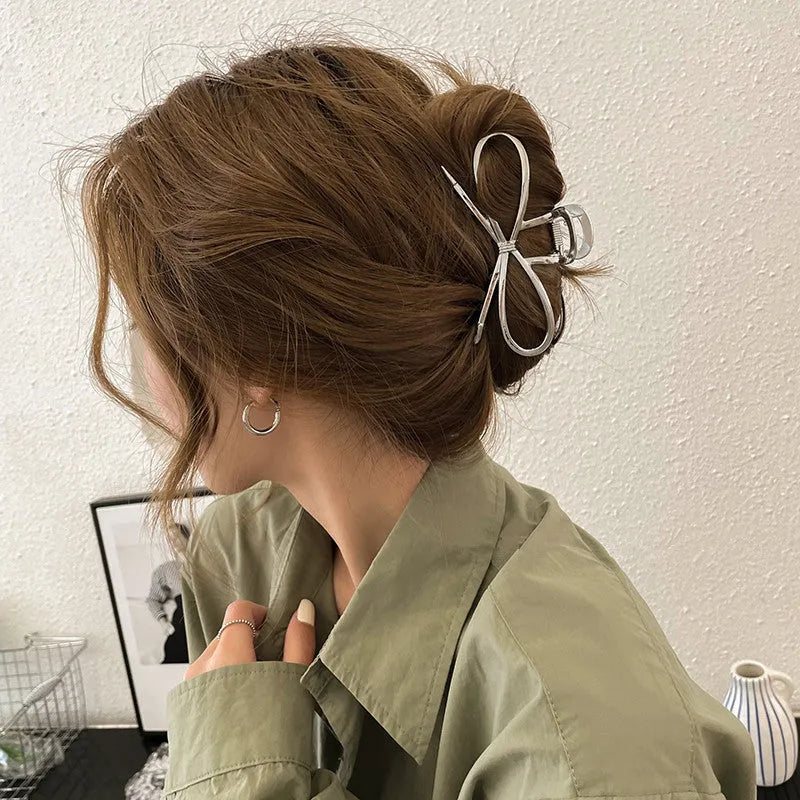 Close-up of a women's gold alloy hair barrette with a bow design and secure clip.