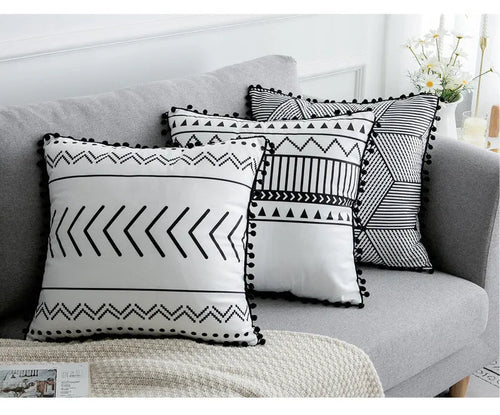 Bohemian style decorative throw pillow with polyester cover in light grey on a sofa.
