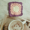 Handcrafted crocheted wool coaster with Grandmother Lattice stitch in a purple colour.