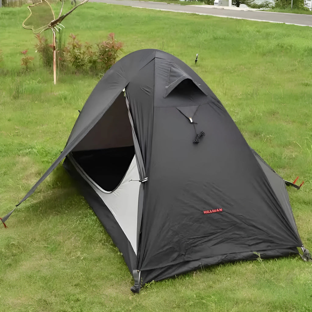 Red single-person double-layer backpacking tent with aluminium poles pitched in a grassy field