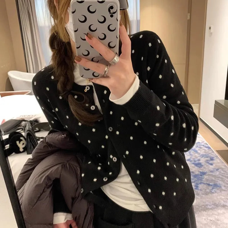 Women's loose grey dot patterned knitted cardigan with crocheted flower details on the front.