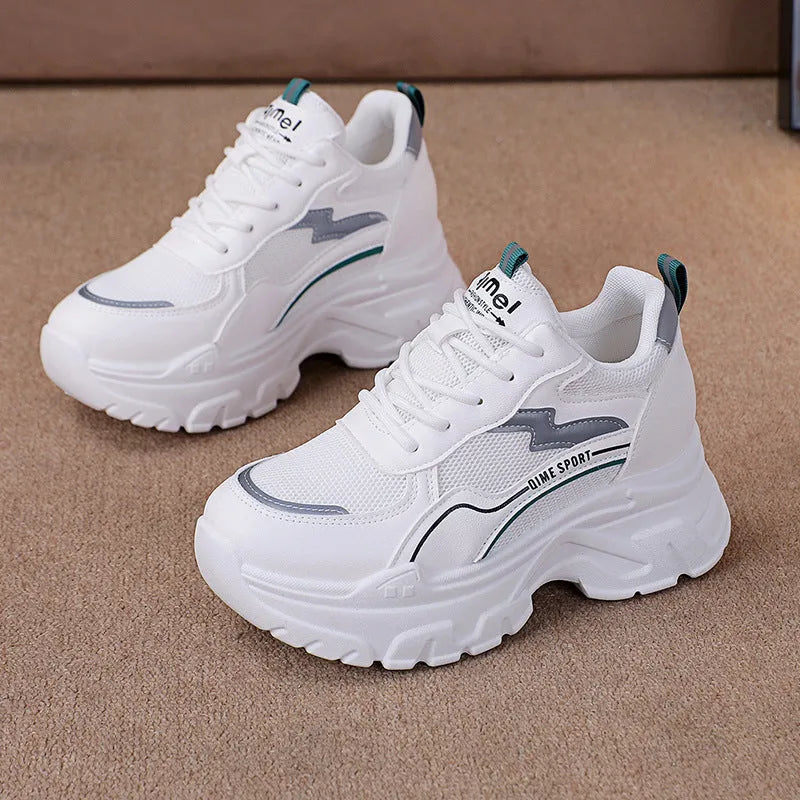 Women's white low-top sports trainers with cross shoulder straps and a lace-up front on a solid background.