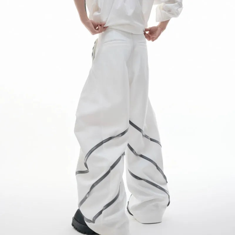 Men's black trousers with pleated detail and metal rivets, showing three-dimensional cut.