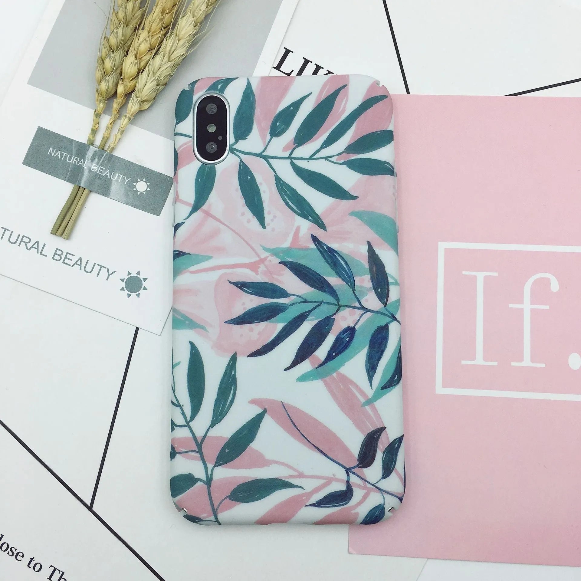 Green and pink painted hard PC back cover cases for smartphones on a table.