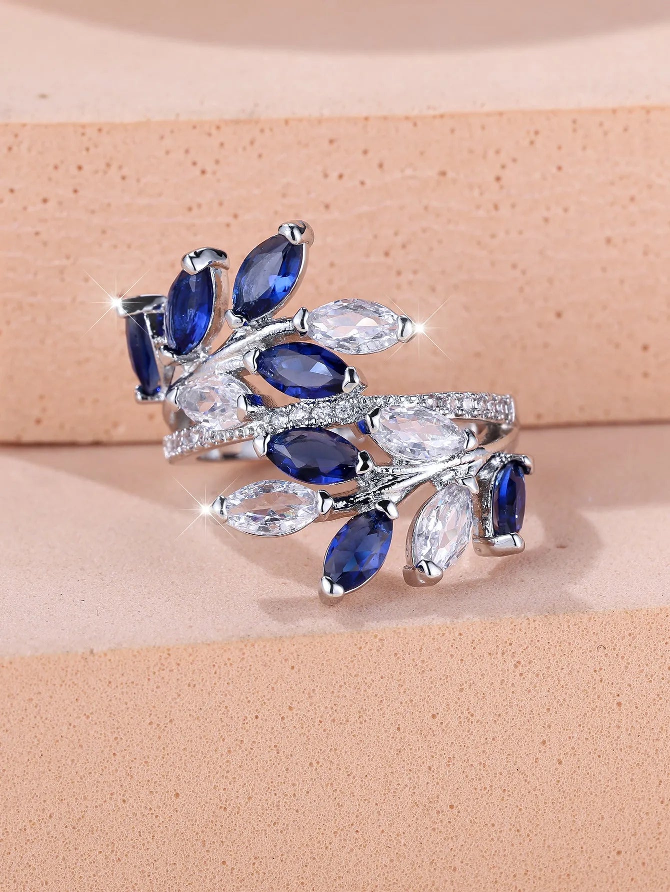 Adjustable copper leaf ring with a central zircon stone on a finger, showing rose gold and platinum colour options.