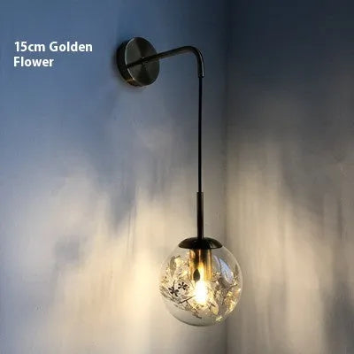 Modern golden flower glass wall lamp mounted beside a bed.