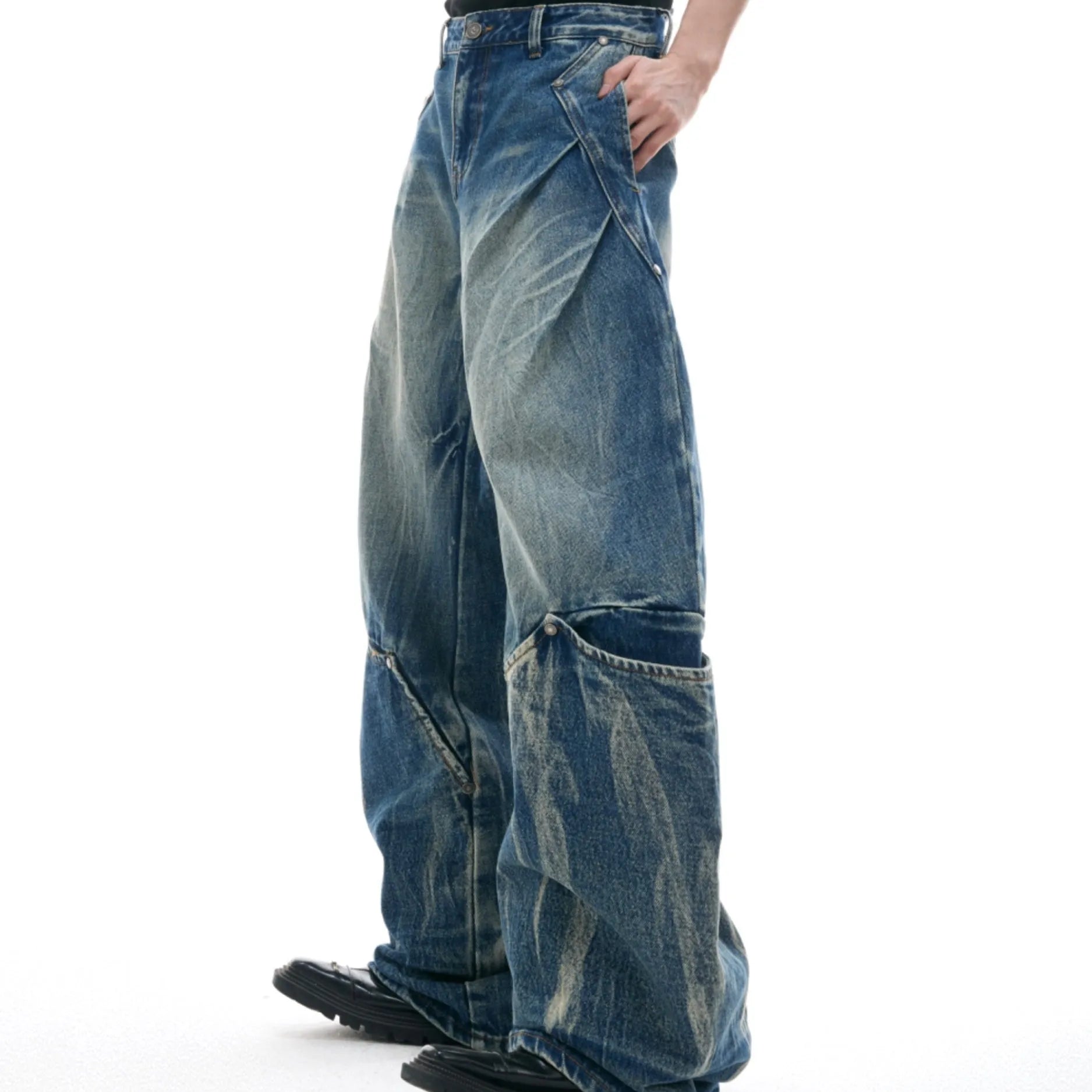 Man wearing verdant blue loose-fit curved knife jeans with a retro washed burst pattern, showing front and side view.