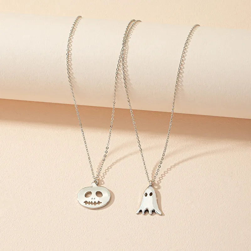 Two silver alloy pendant necklaces: one cartoon pumpkin and one cartoon ghost on a light background