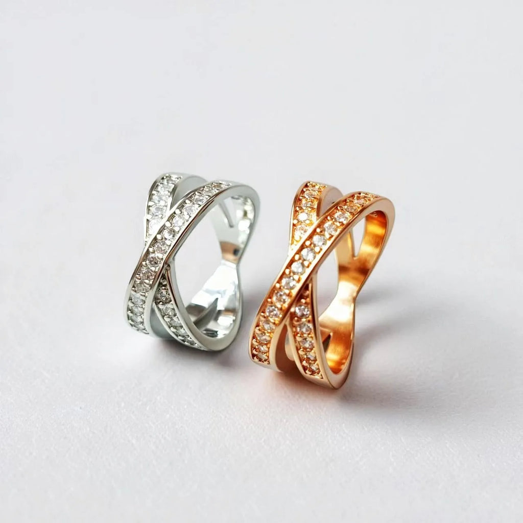 A silver or rose gold metal ring featuring a heart-shaped cross centrepiece with micro-inlaid zircon details.