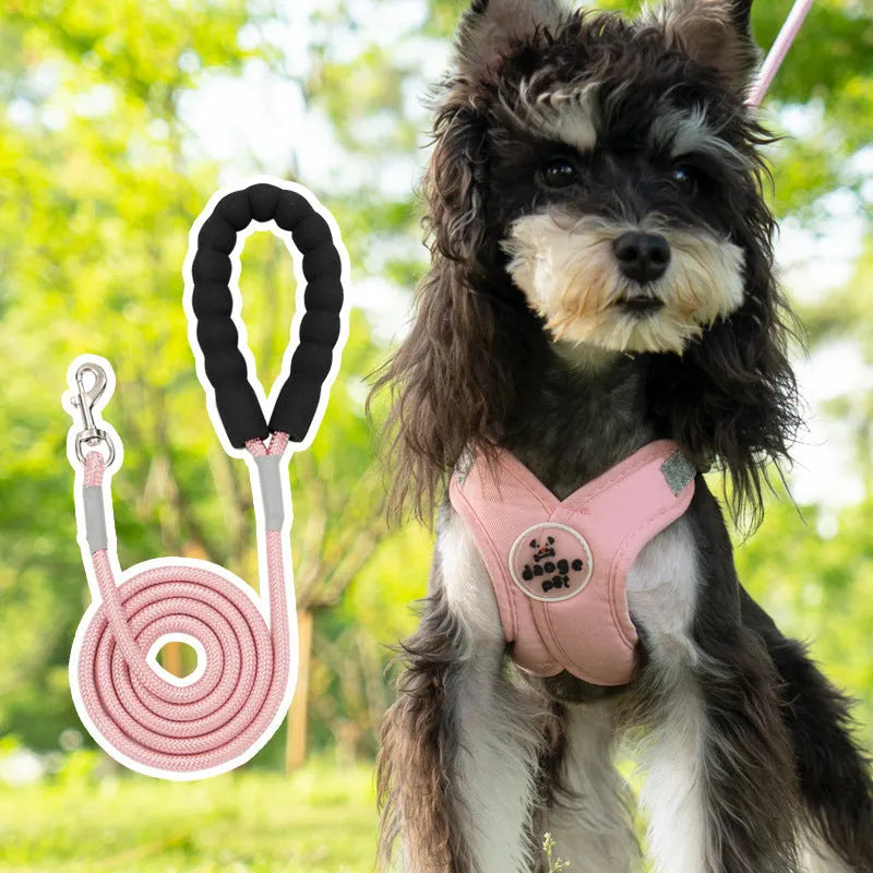 Pink polyester dog vest with an attached hand holding rope laid flat