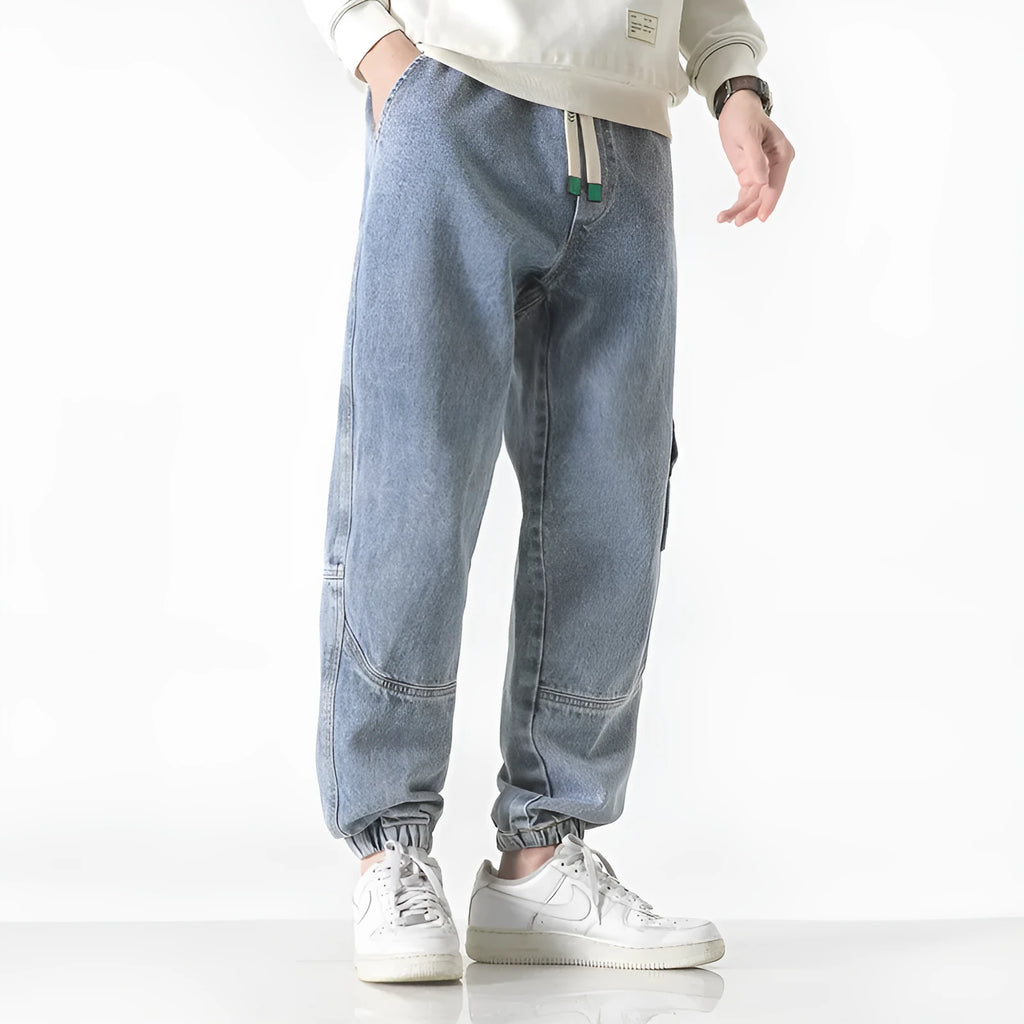Men's loose-fit tapered cotton trousers in grey colour, shown on a model.