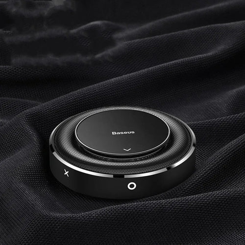 Round black aluminium alloy Bess car fragrance unit placed on a car seat.
