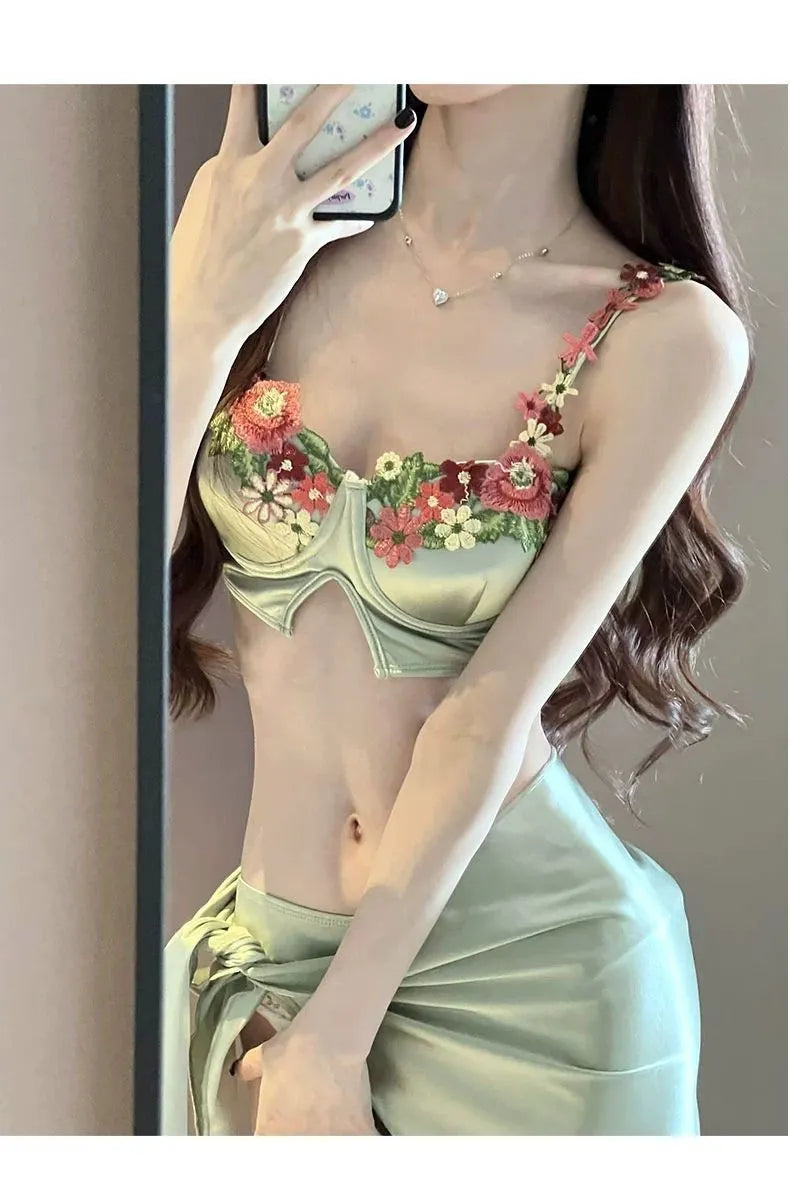 Green women's three-piece bikini set showing sleeveless triangle top, briefs, and a skirt on a mannequin.