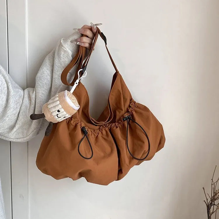 Ultra-light foldable pleated crossbody bag in polyester showing split pockets and mobile phone compartment.