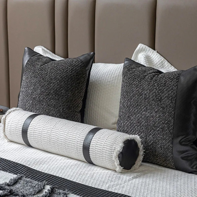 Modern grey and white plaid bed runner set with matching pillowcase and a brown leather round pillow on a bed.