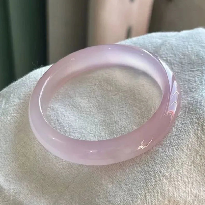 Natural agate wide tire bracelet in pink on a wrist, showing polished bead design.