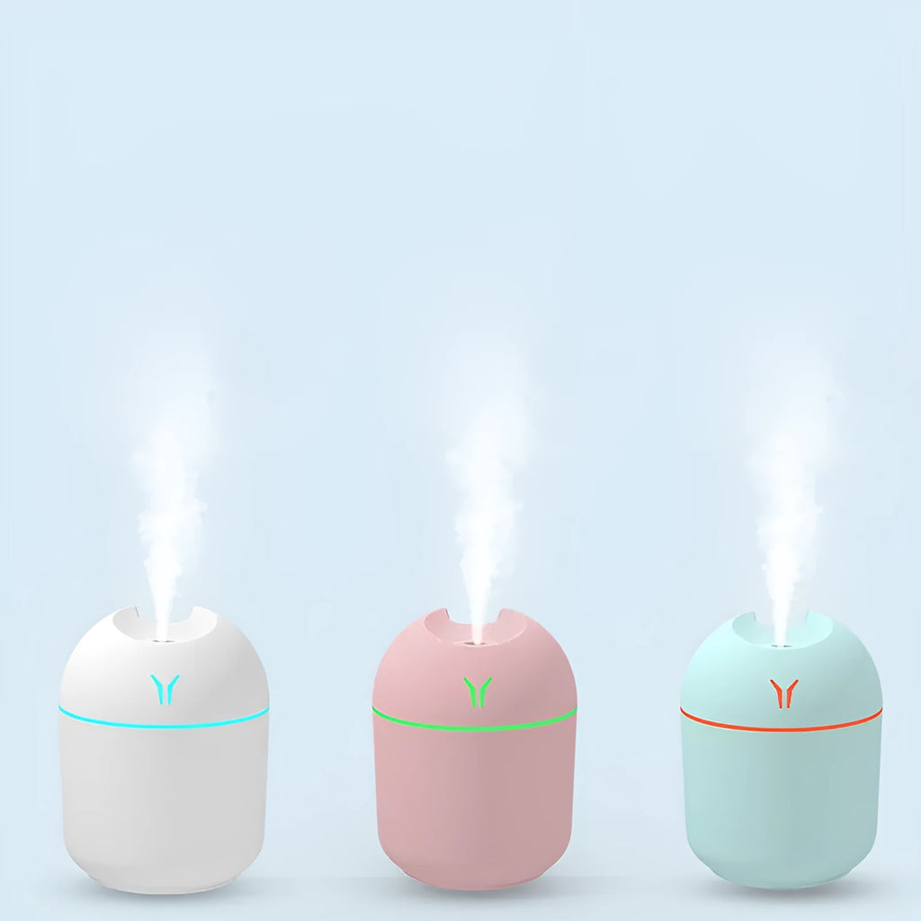 Compact round desktop humidifier with USB cable in ivory white, sky blue, or pink.