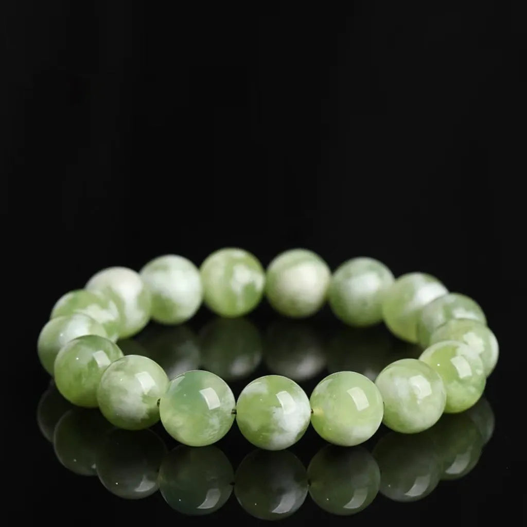 Green milk-in-water Xiuyan jade bracelet with geometric beads on white background