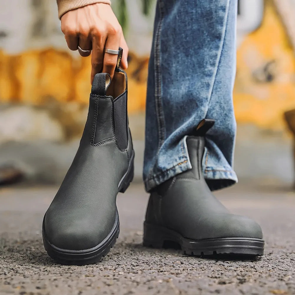 Vintage brown unisex Chelsea boot with frosted PU upper and car suture detailing on a wooden floor.