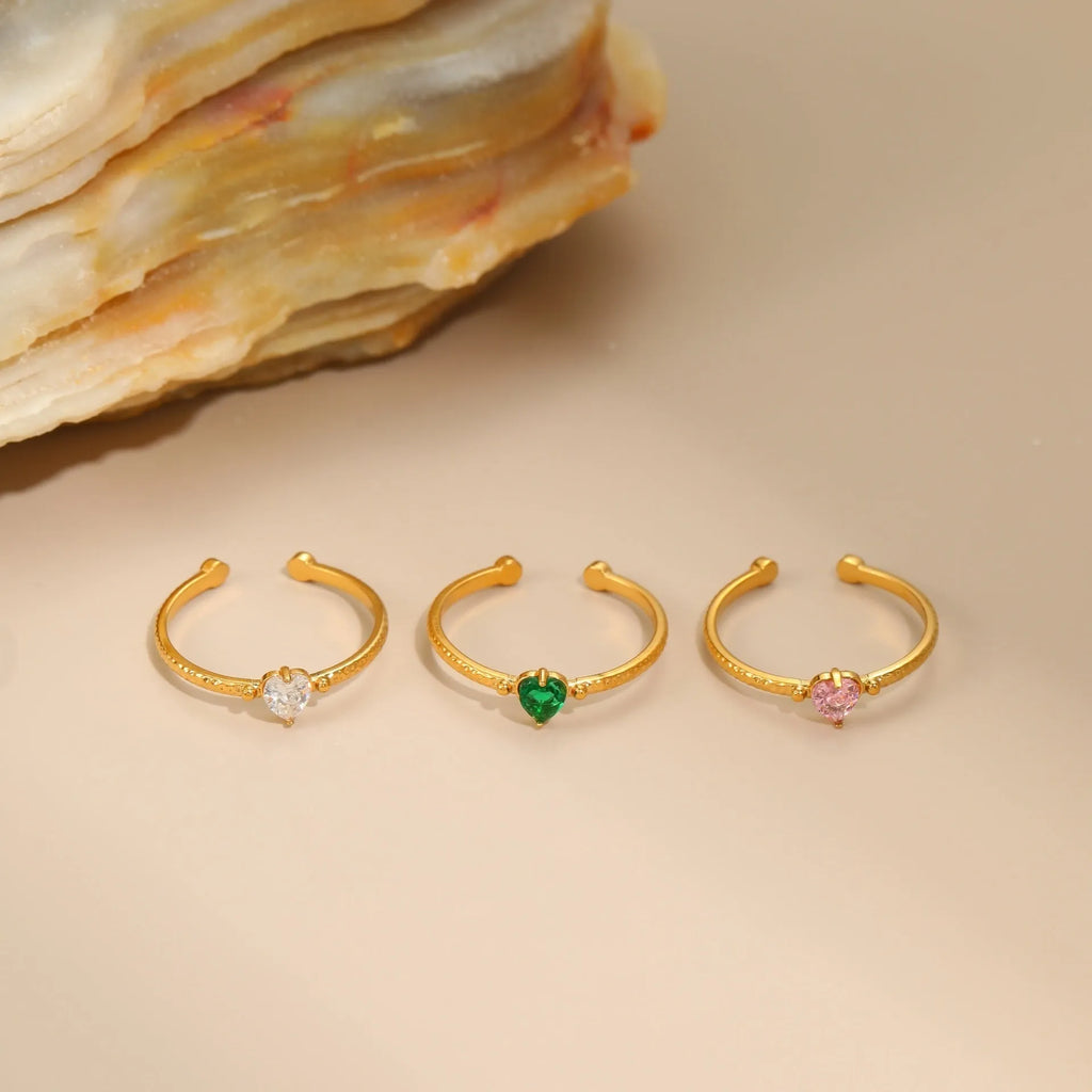 Geometric open-ended heart-shaped stainless steel ring with inlaid zircon detail in white, pink, or green.