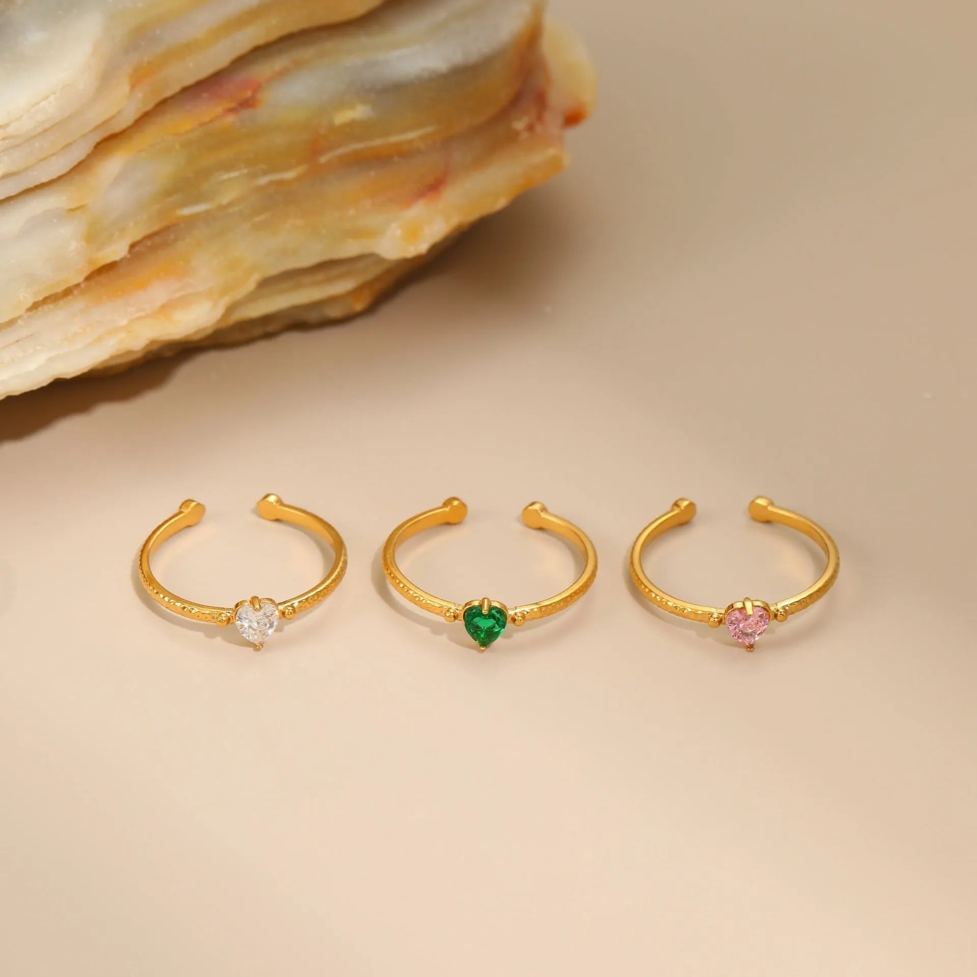 Geometric open-ended heart-shaped stainless steel ring with inlaid zircon detail in white, pink, or green.
