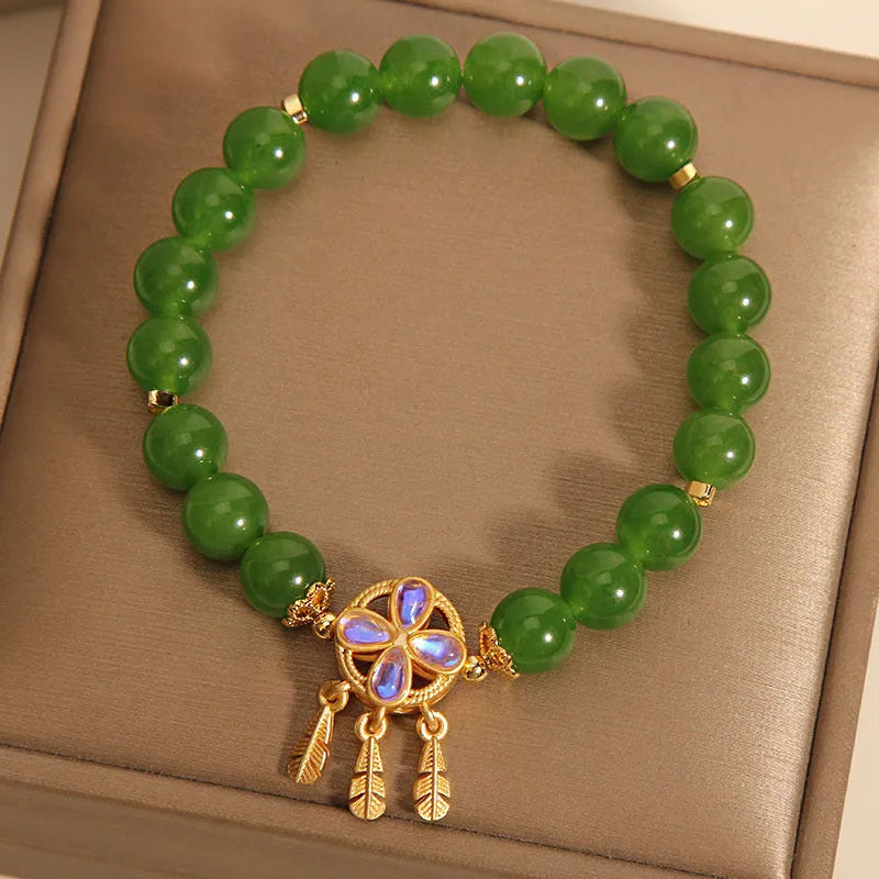 Green Jasper crystal bracelet with a four-leaf clover dream catcher pendant on a woman's wrist.
