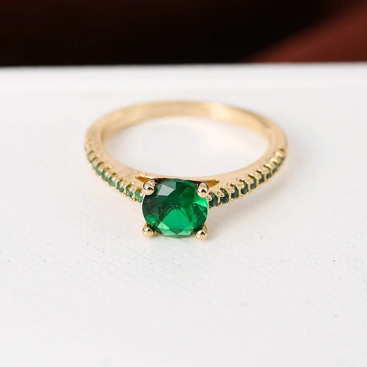 Geometric hexagonal copper ring with a zircon stone, shown in a gold rose red electroplated finish on a size 7 finger.