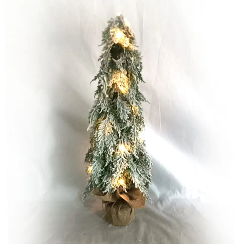 Small 24-inch plastic Christmas tree with LED lights and snow-covered branches on desktop