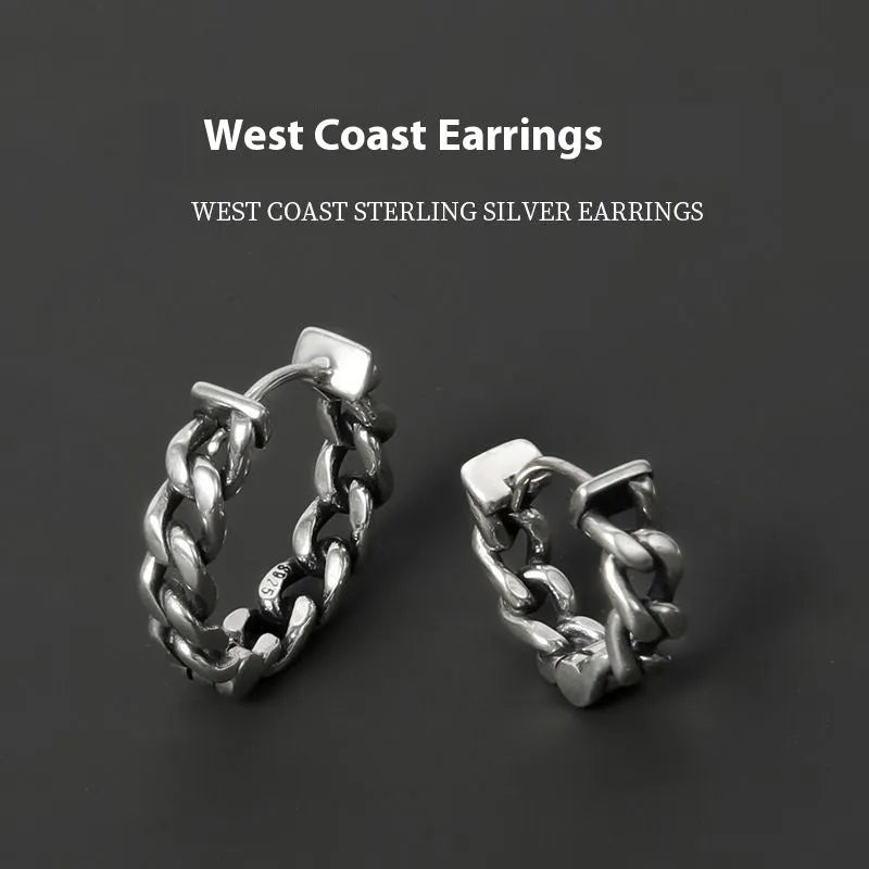 Close-up of a pair of men's geometric copper hip hop earrings on a dark background.