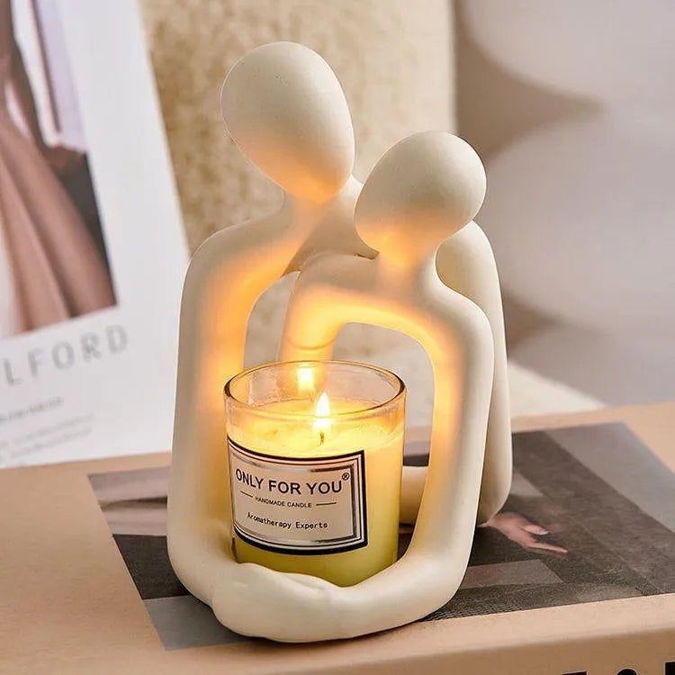 Modern resin couple statue in milky white or gold colour on a wooden surface.