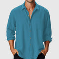 Man wearing a loose fit long sleeve shirt with a stand collar on a beach.