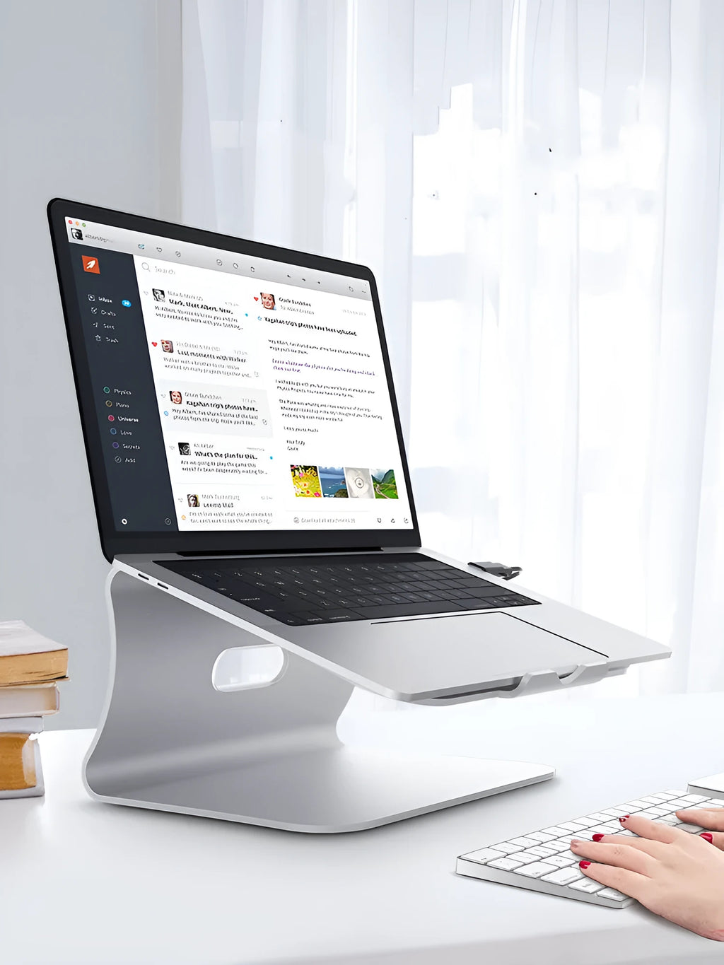 Silver aluminium laptop cooling stand with rotary base on a wooden desk, elevating a laptop.