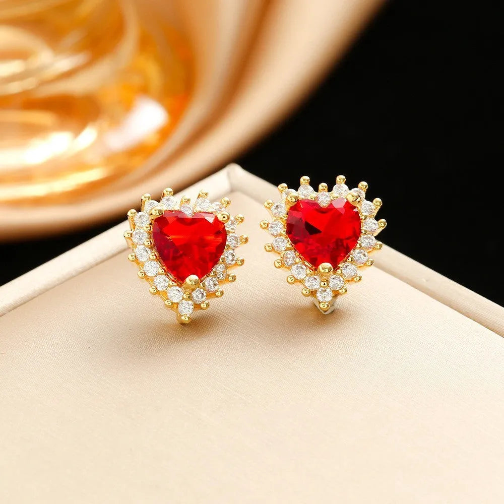 Gold-red titanium steel necklace with heart flower pendant, matching stud earrings, and ring on a grey background.