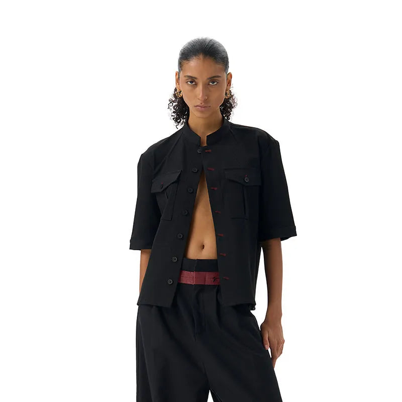 A black loose fit half sleeve hunting shirt with a shirt collar on a hanger.