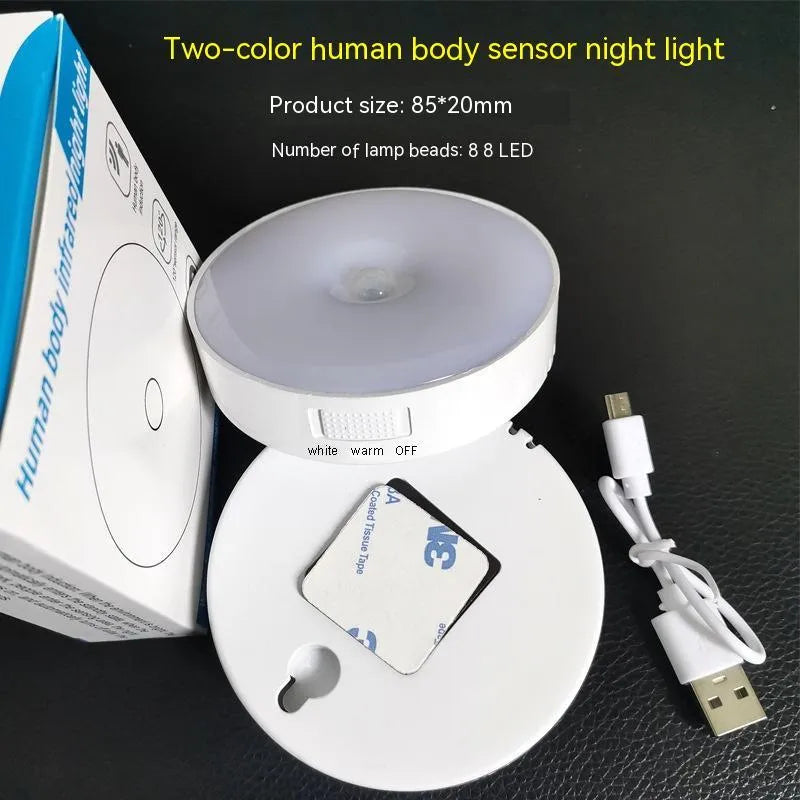 Compact round beige motion sensor LED night light with USB charging cable on a wooden surface
