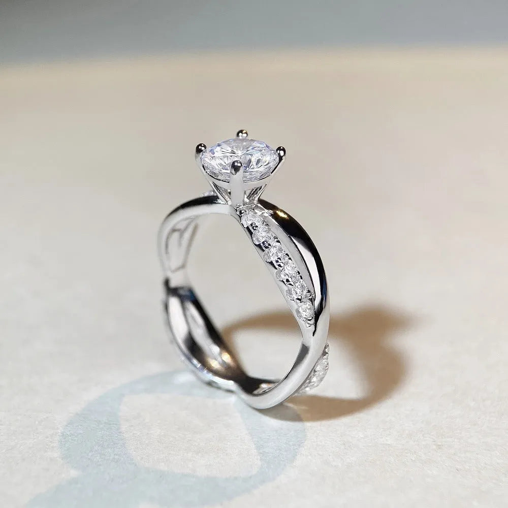 Geometric cross design silver ring with a 1 carat moissanite stone and twisted arm winding.