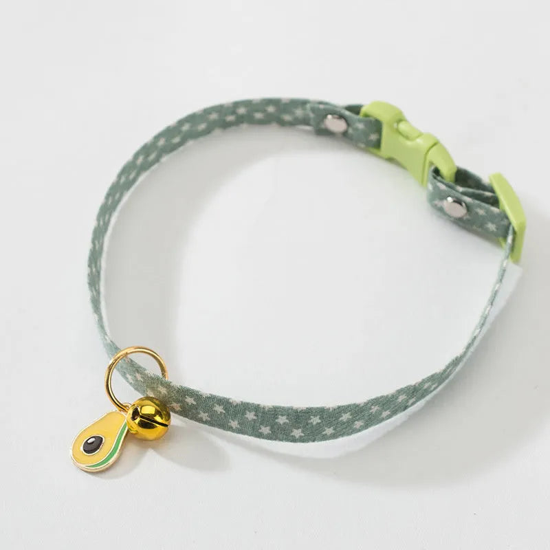 Adjustable green cat collar with a metal bell and a red bow tie pendant fastened around a small dog's neck.