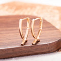 A pair of rose gold coloured cross shaped earrings on a copper metal base.