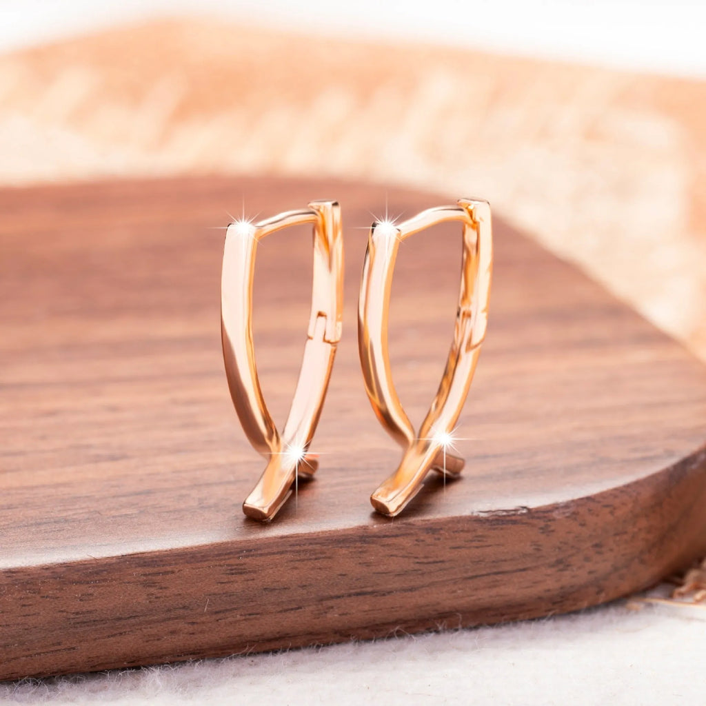 Rose gold coloured copper cross shaped earrings on a flat surface.