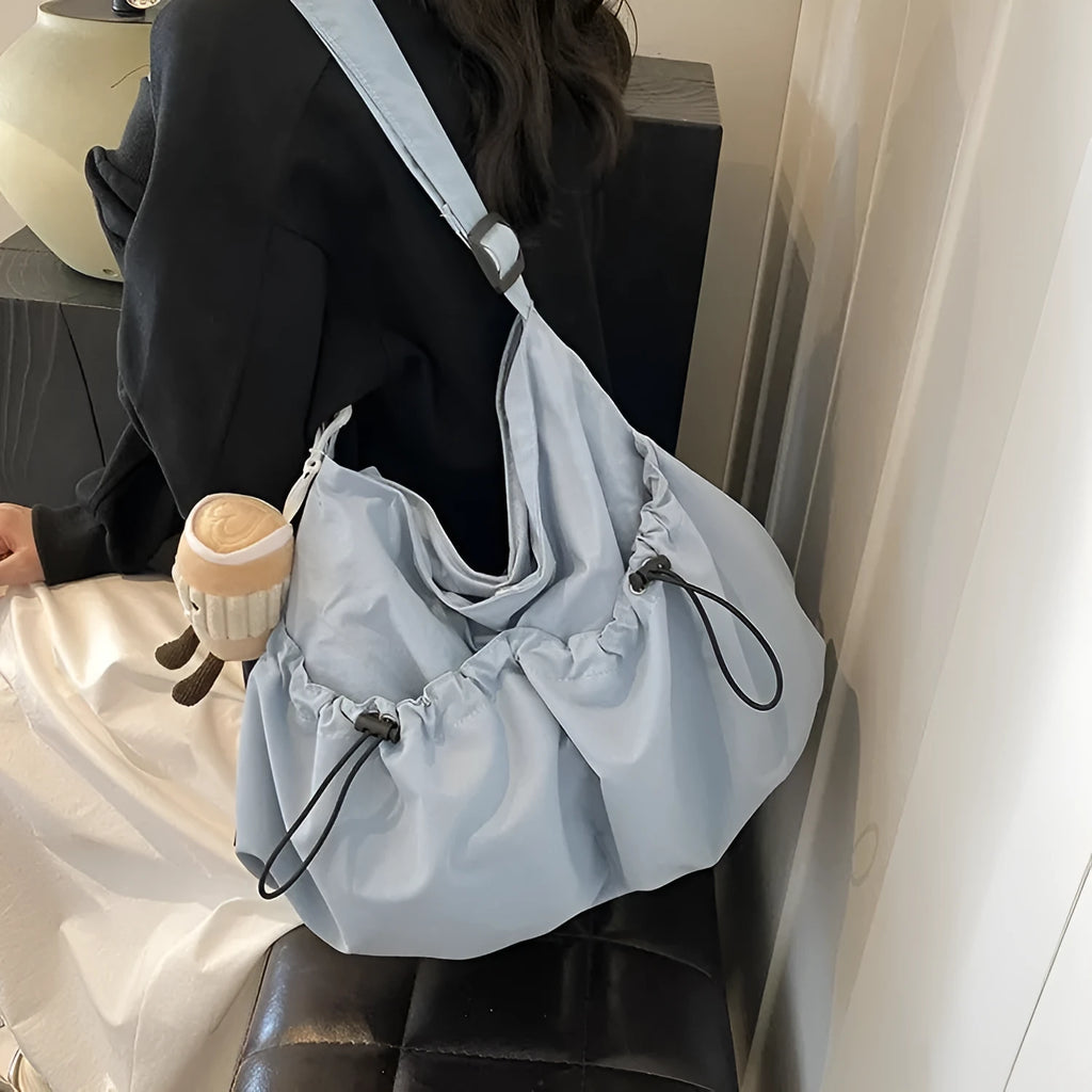 Ultra-light foldable pleated crossbody bag in polyester showing split pockets and mobile phone compartment.
